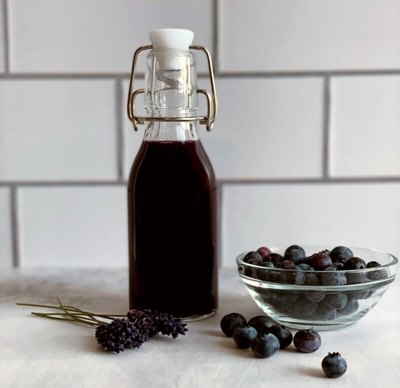 blueberry lavender syrup, a bowl of fresh blueberries and fresh lavender sprigs