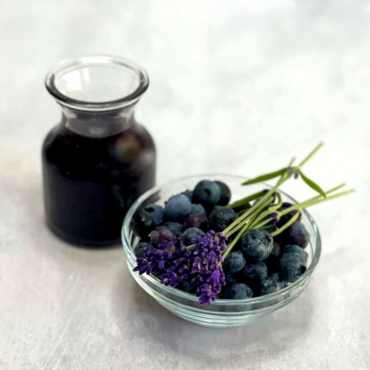 fresh blueberries in a bowl and a jar of blueberry lavender syrup