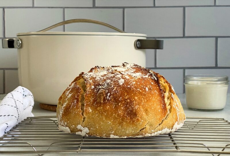 dutch oven sourdough bread loaf in front of caraway dutch oven