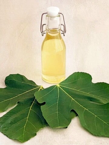 fig leaf syrup in a bottle on top of fresh fig leaves