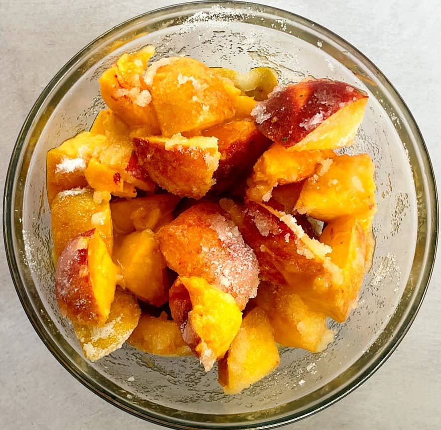 sliced peaches and sugar in a bowl.