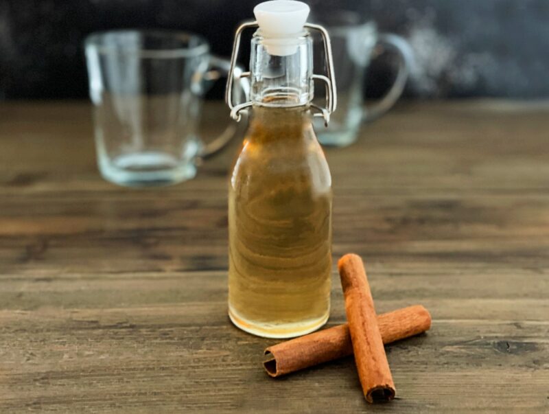 cinnamon syrup in a sealable bottle and fresh cinnamon sticks