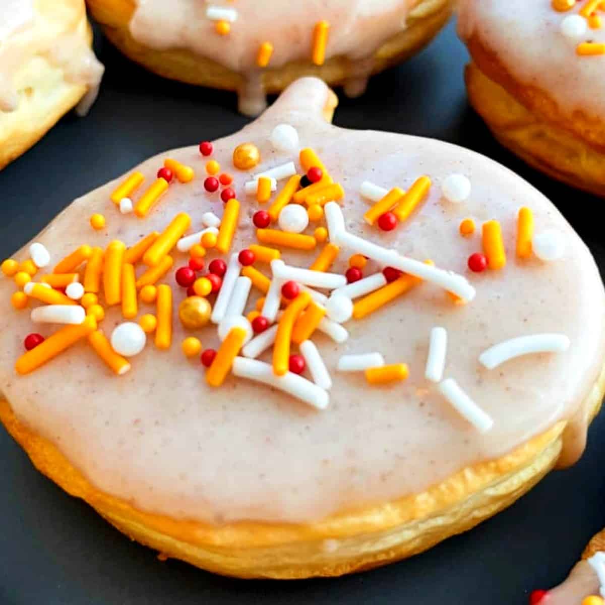 pumpkin spice donut with orange and white sprinkles on top.