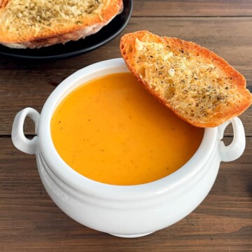 tomato soup in a bowl with garlic bread
