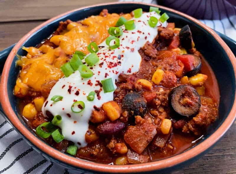 a bowl of 30-minute chili with melted cheese, green onion, and sour cream on top