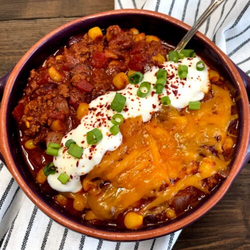 a bowl of chili with sour cream and cheese on top