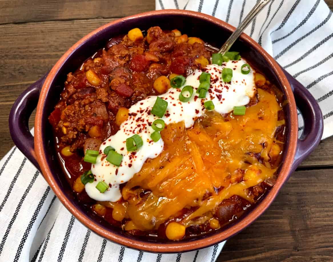 a bowl of chili with sour cream and cheese on top
