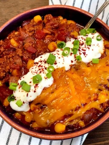 bowl of chili with sour cream and cheese on top
