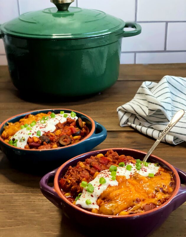 homemade chili recipe served in bowls with melted cheese and sour cream on top