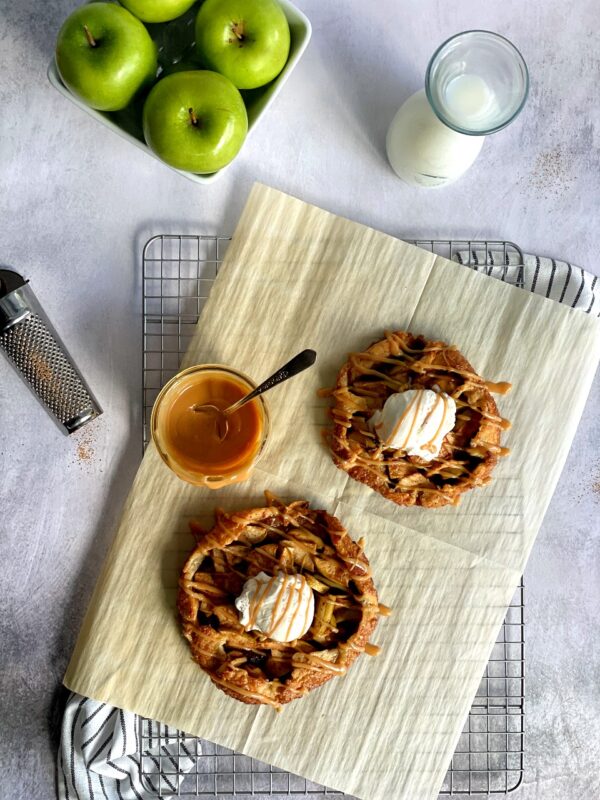 mini salted caramel apple galettes on a cooling rack with a jar of caramel