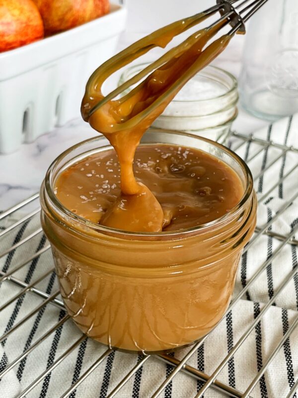 salted dulce de leche dripping off a whisk into a jar