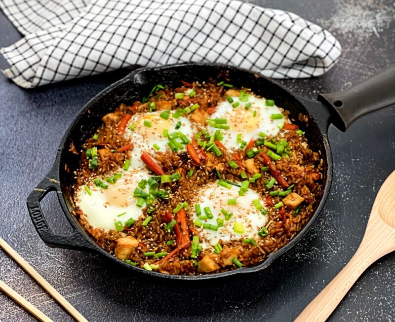 chicken fried rice with baked eggs in a cast iron pan