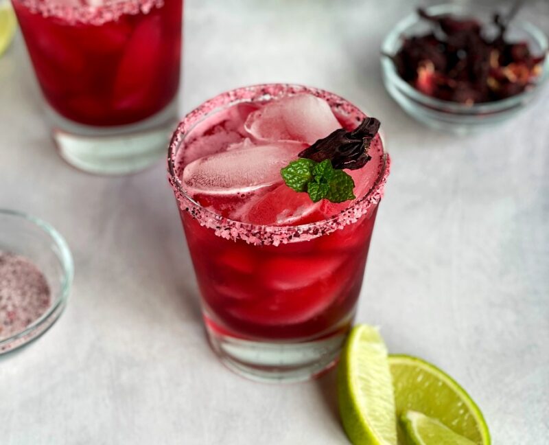 hibiscus margaritas with hibiscus salt, a dried hibiscus flower and fresh mint sprig.