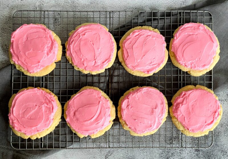 crumbl cookie copycat cookies with pink frosting on a cooling rack
