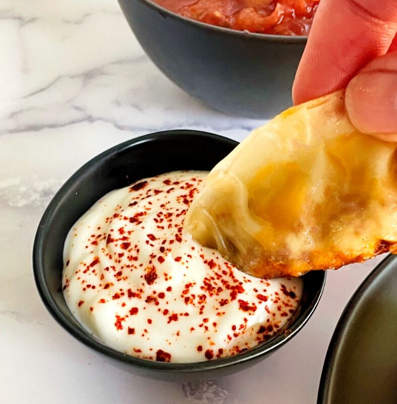 taco dumpling being dipped in sour cream