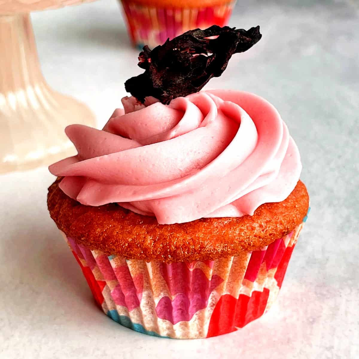 hibiscus cupcake with a dried hibiscus flower on top of hibiscus buttercream.