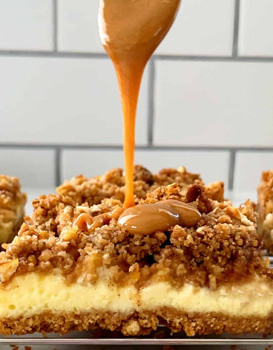 a drizzle of caramel on top of an apple cheesecake bar.