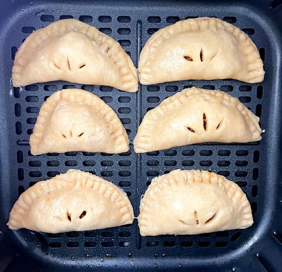 taco hand pies in air fryer basket before cooking.
