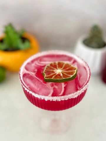 prickly pear margarita with dried lime wedge garnish.