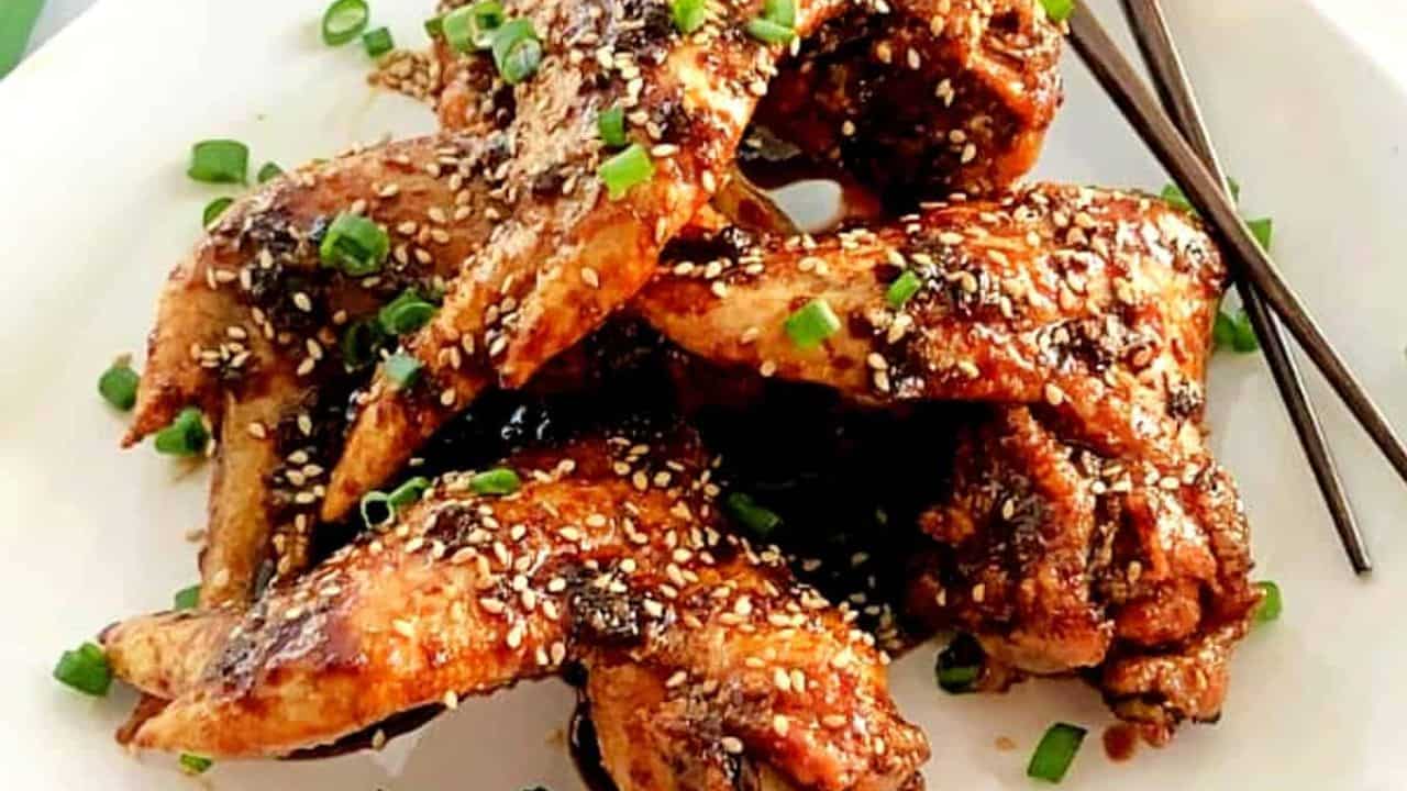 baked Asian chicken wings in a white plate with chopsticks
