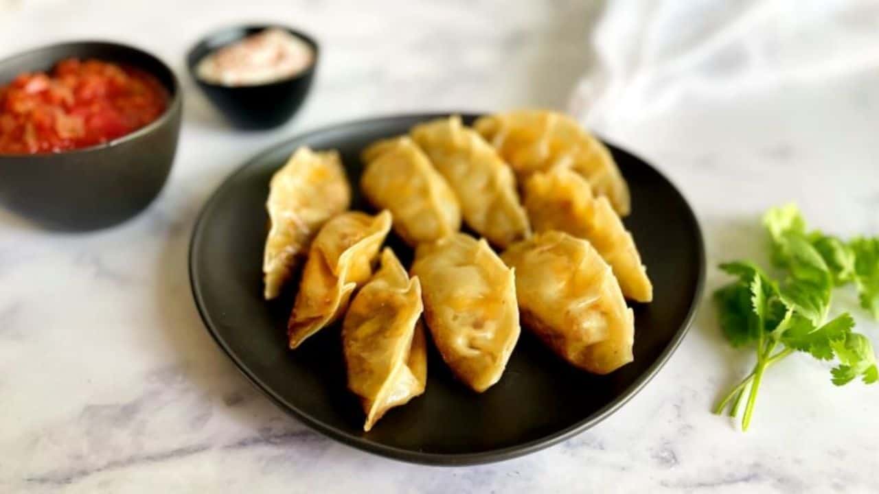 taco dumplings in a black plate with ketchup dipping sauce