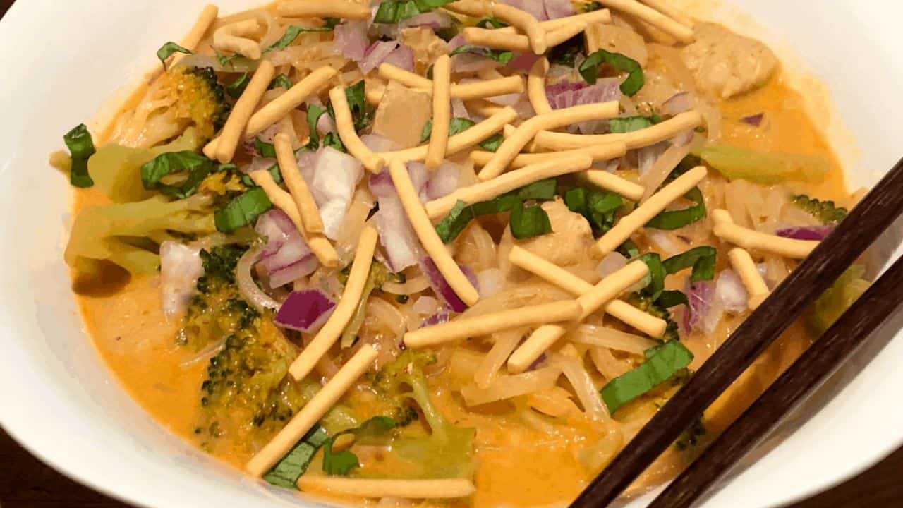 a white bowl of Thai red curry noodle soup