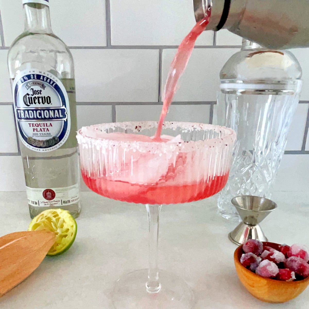 shaker pouring cranberry margarita into a glass.