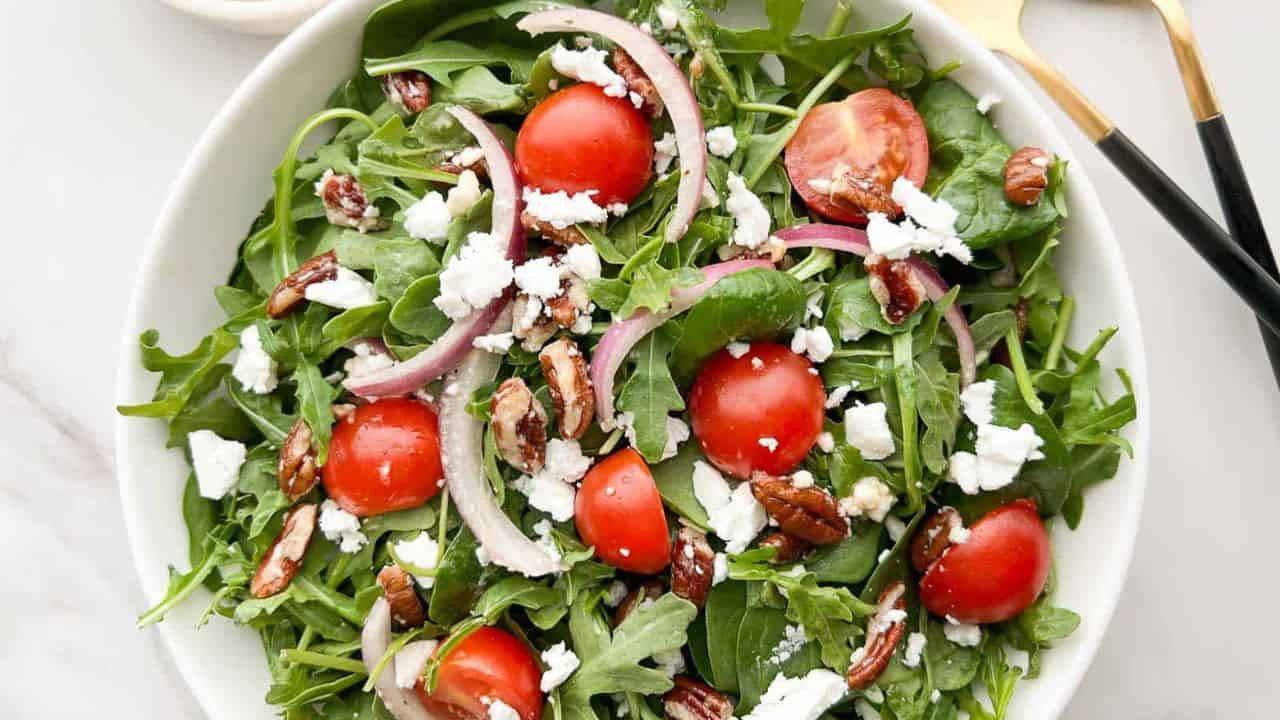 Healthy arugula salad with cherry tomatoes, red onions, walnuts, and feta cheese. Perfect for a ligh.