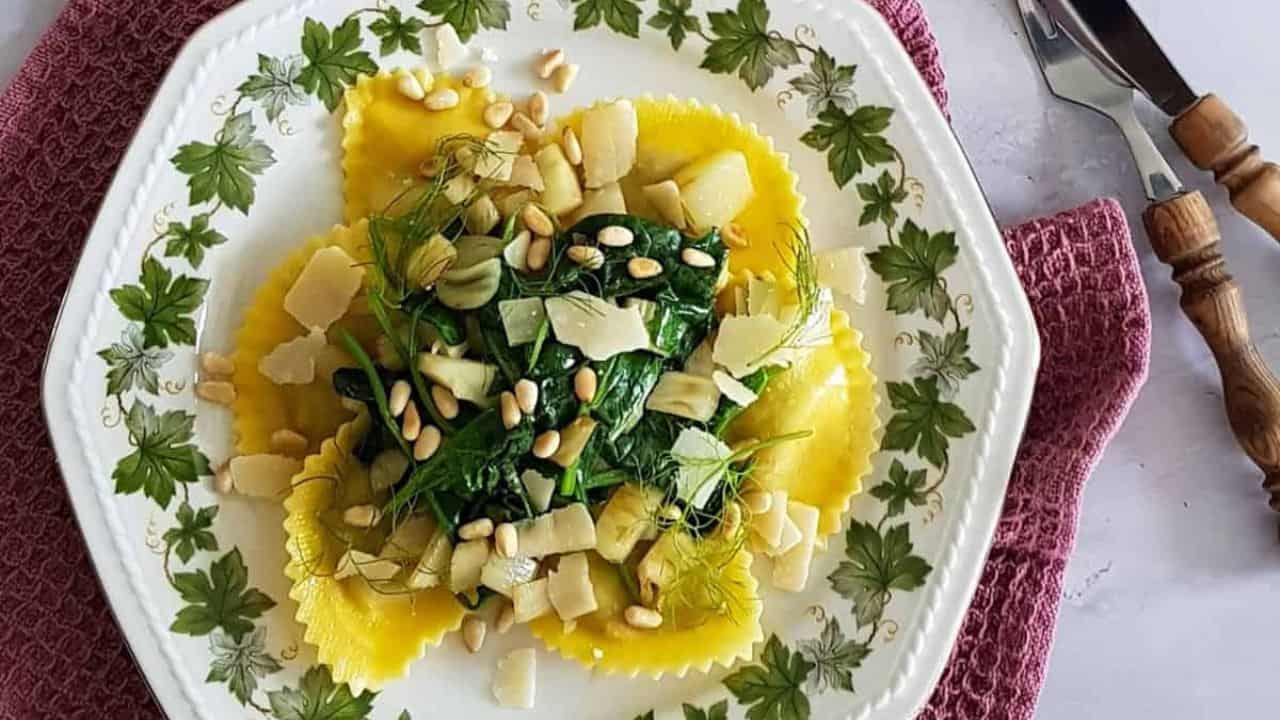 Delicious homemade ravioli filled with spinach, topped with pine nuts and cheese, served on a floral.