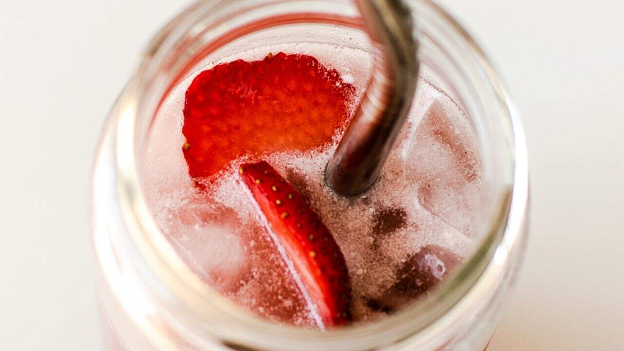 Refreshing strawberry iced coffee with fresh fruit and ice cubes.