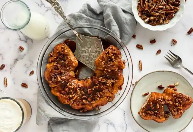 Delicious sweet potato casserole topped with pecans, served on a marble table.